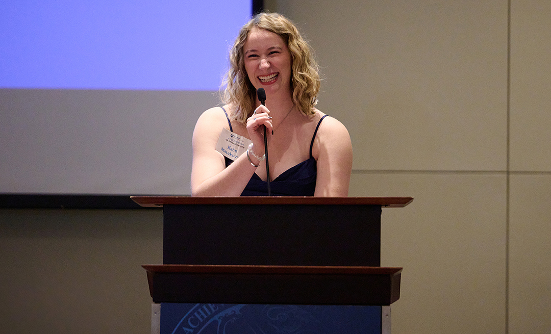 an individual speaks at a podium in front of a screen